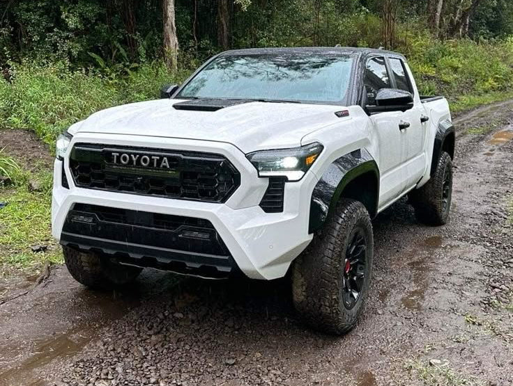 White Toyota TRD truck on a muddy road with trees in the background